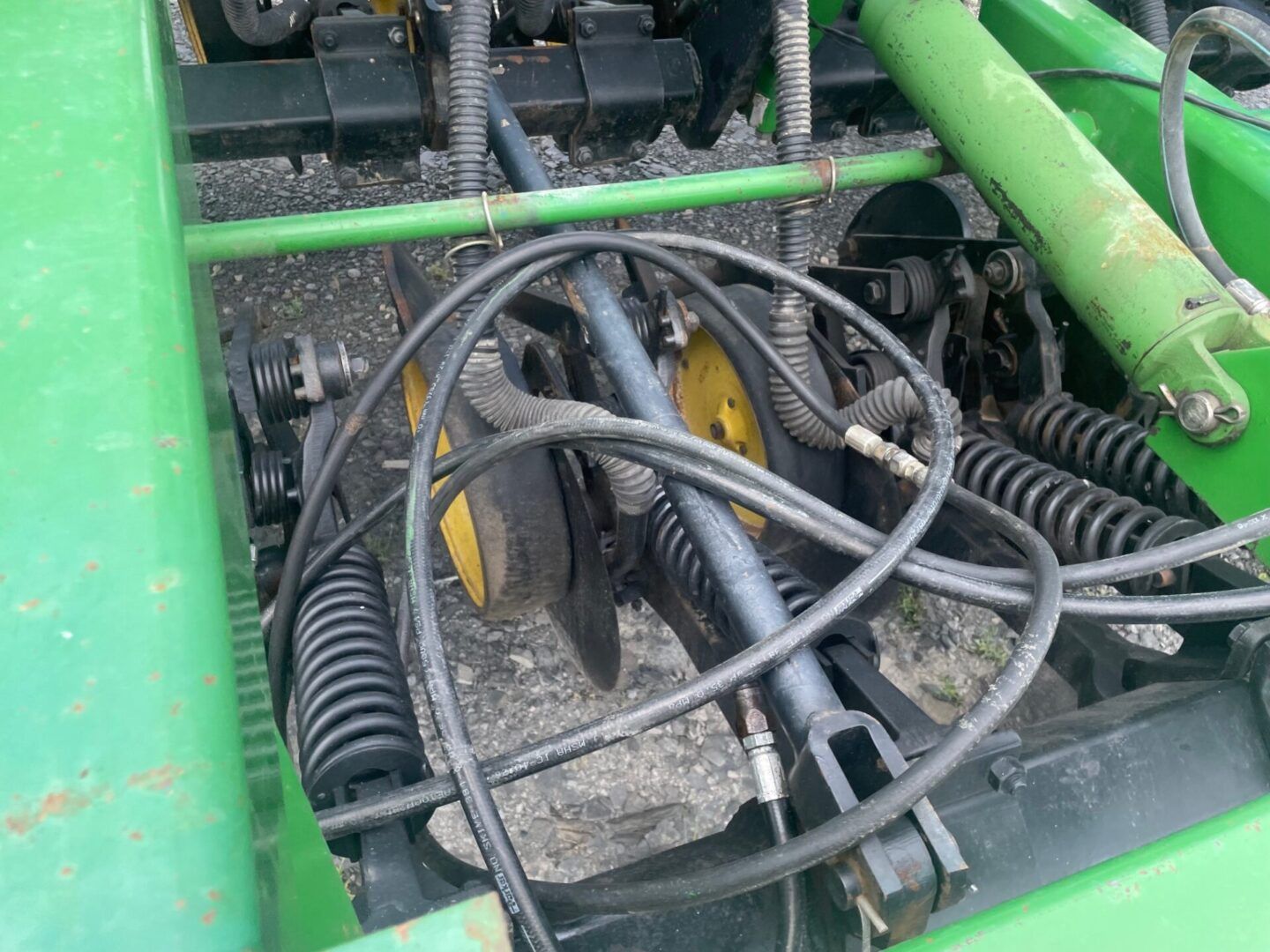 Green machinery with tangled black hoses and cables inside a mechanical compartment