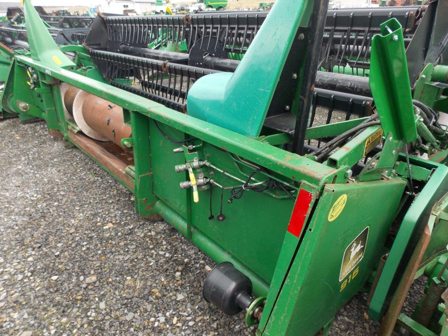 Green farm machinery with metal framework and conveyor parts on gravel