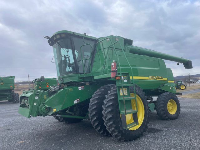 Green combine harvester parked outdoors under cloudy sky