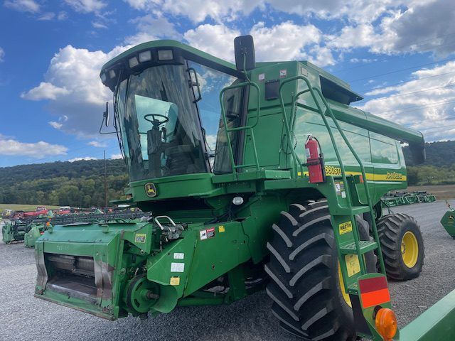 Green combine harvester parked in a field under a cloudy sky