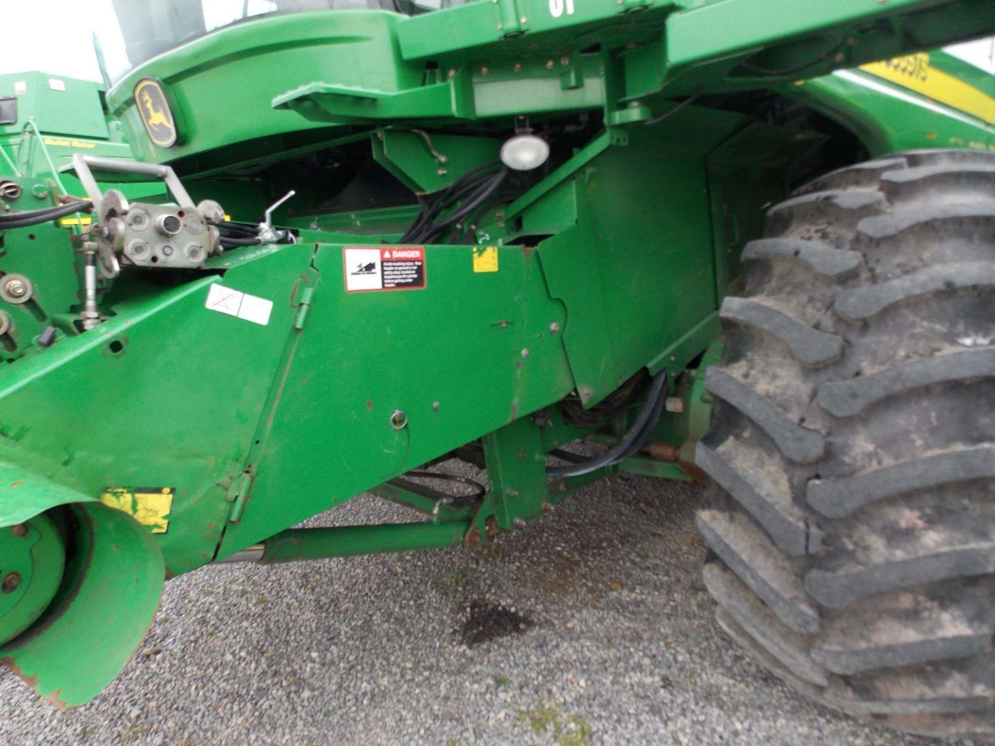 Close-up of a green tractor with large rear tire on gravel