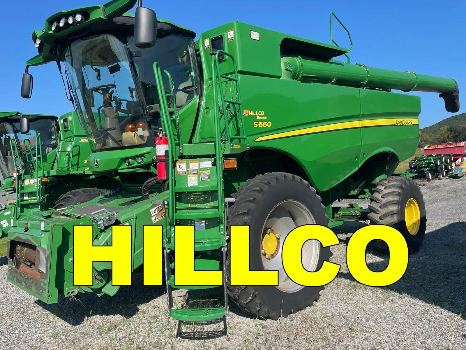 Green HILLCO combine harvester in a field, with yellow logo text in front
