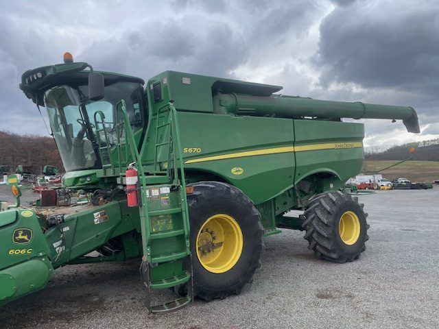 Green John Deere combine harvester parked outdoors under cloudy skies