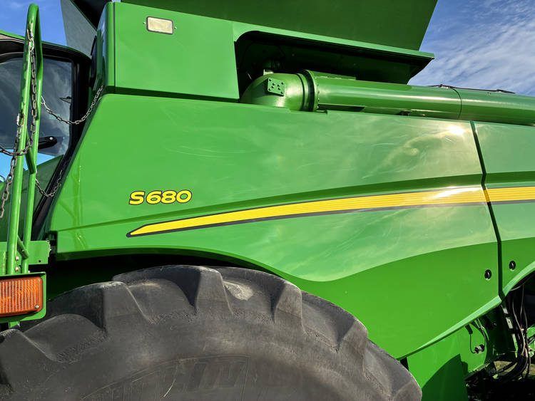 Close-up of a green John Deere 5680 combine harvester with large tire and yellow stripe