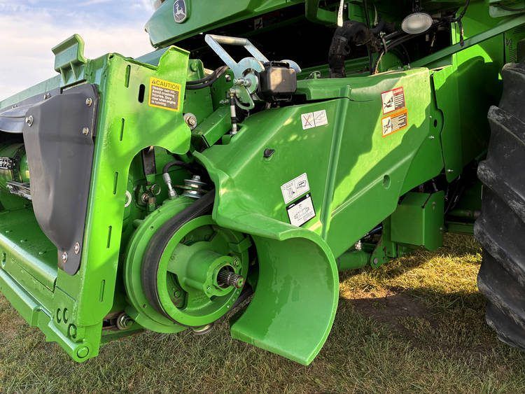 Close-up of a green agricultural machine’s side with large wheel and metal components