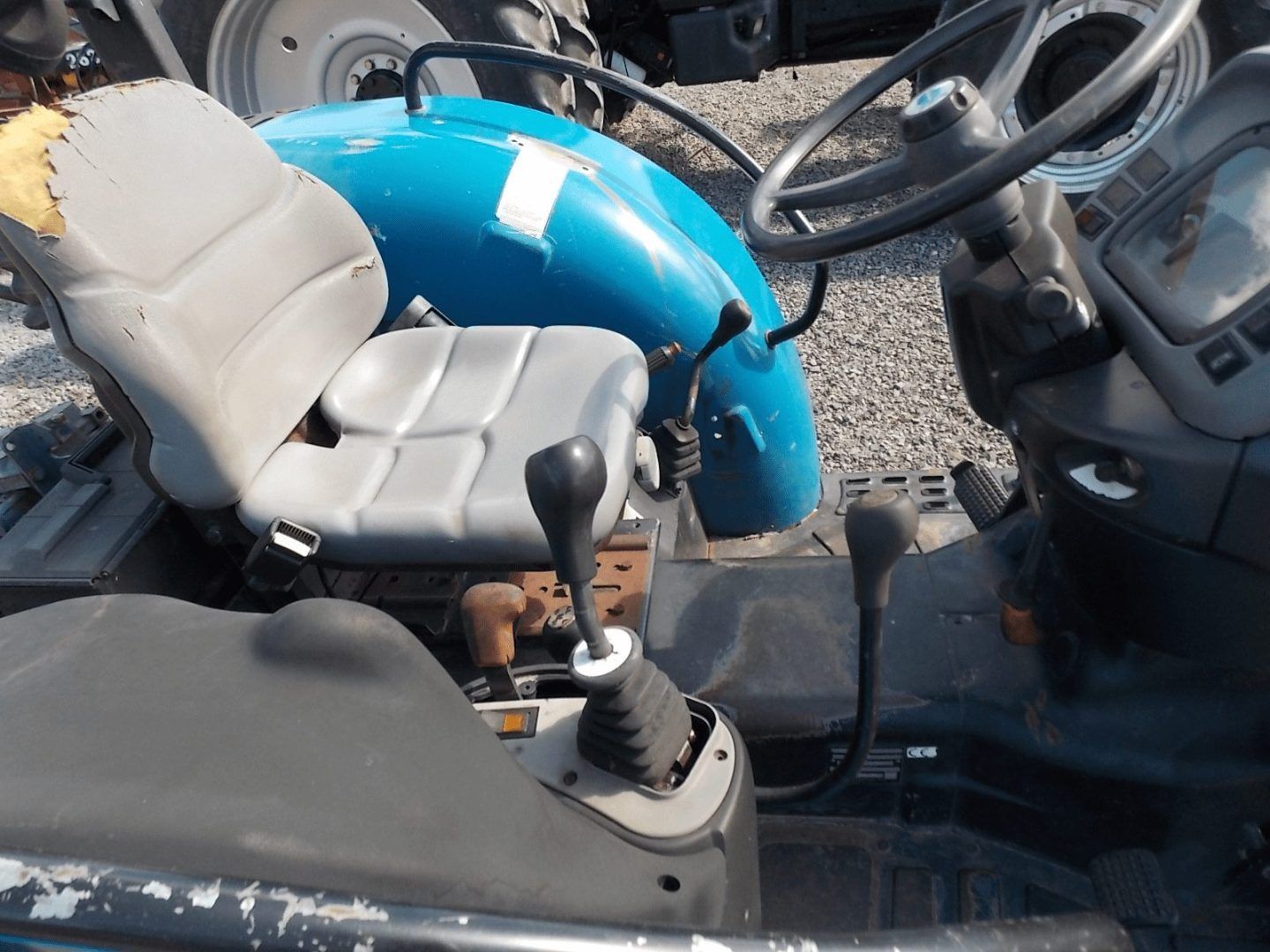 Two seats and controls inside a vehicle cabin, with a bright blue hood visible outside.