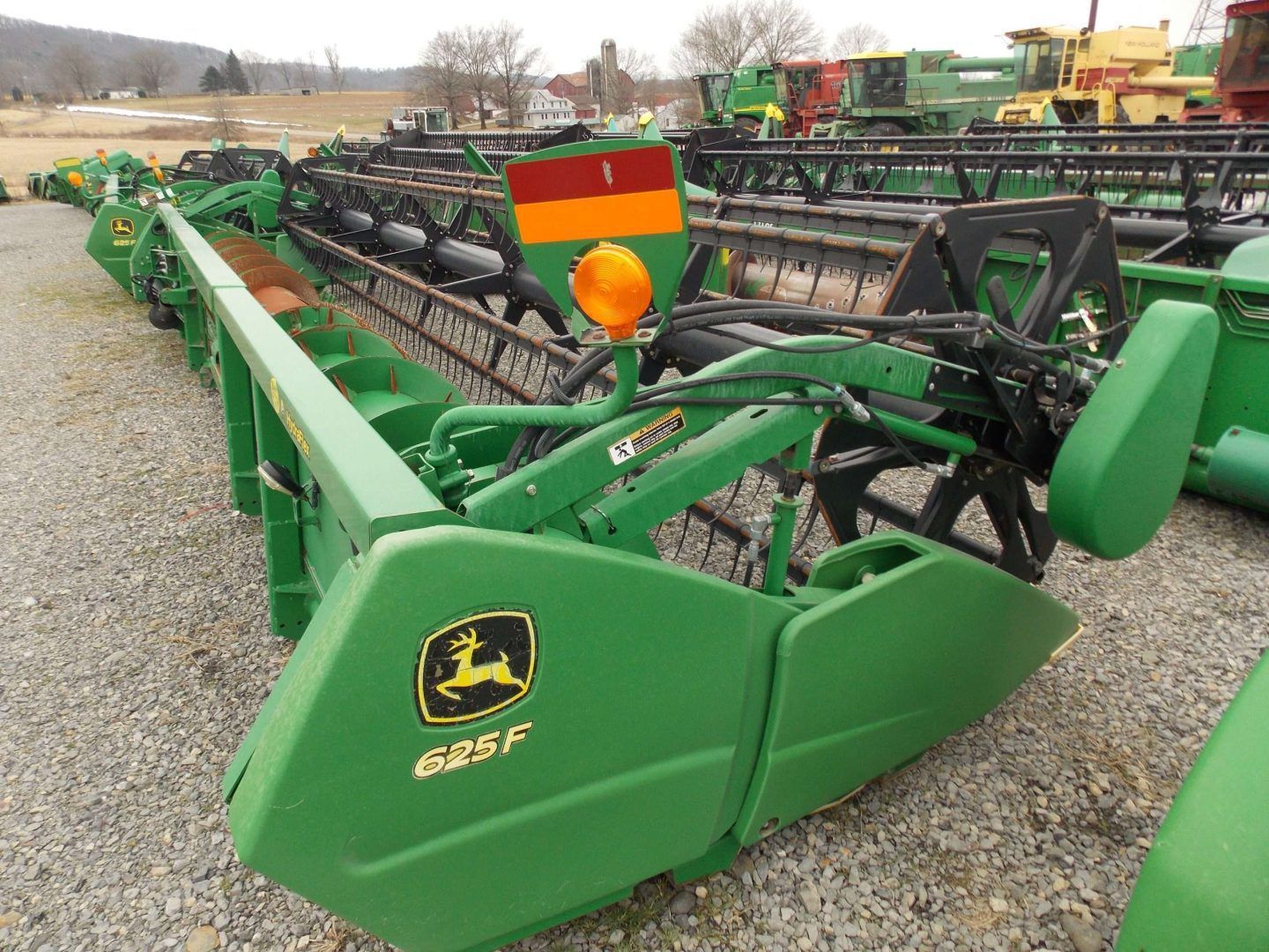 Green John Deere farm implement with black disc rows parked on gravel outdoors