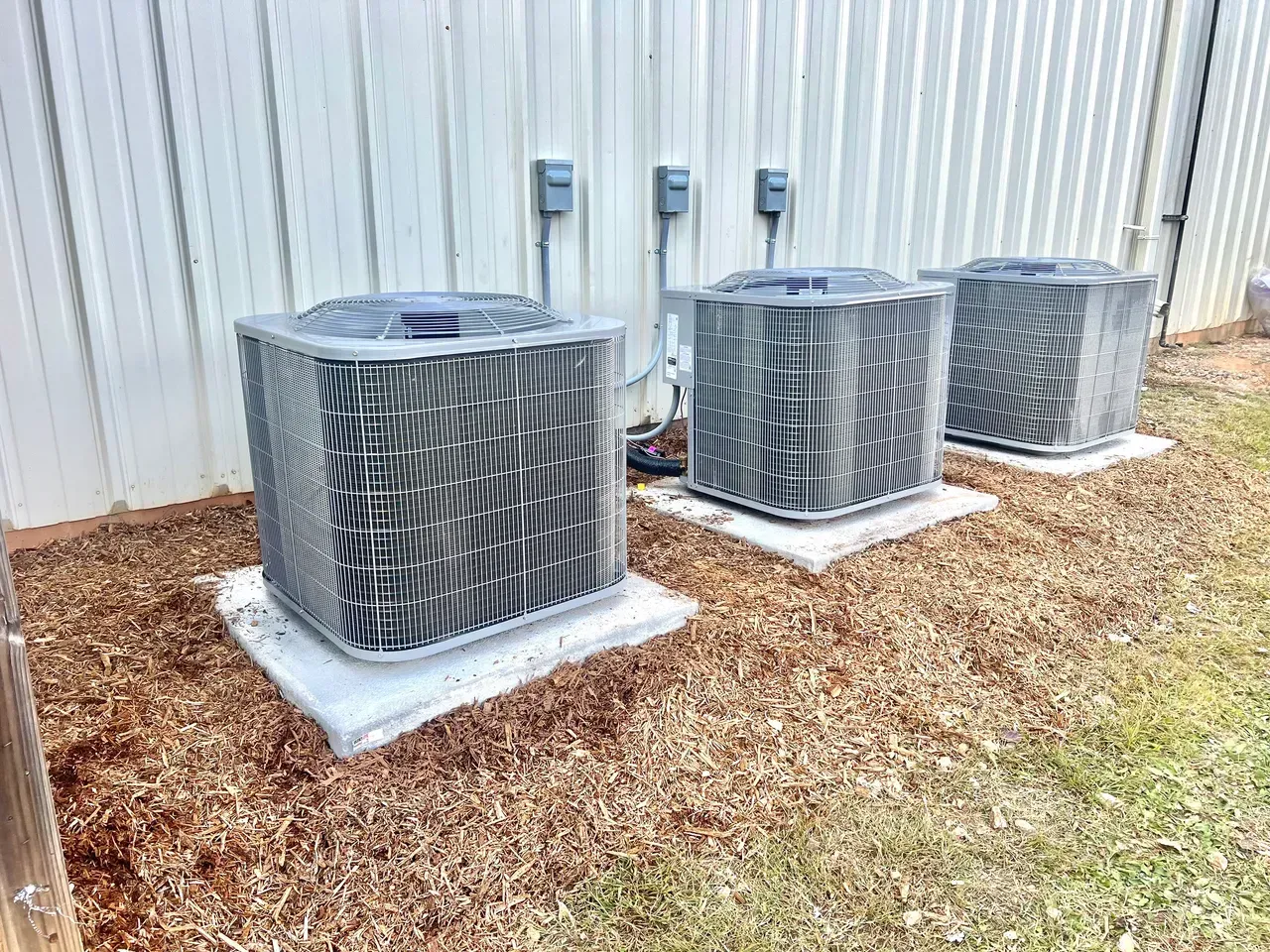 Three air conditioners are sitting next to each other outside of a building.