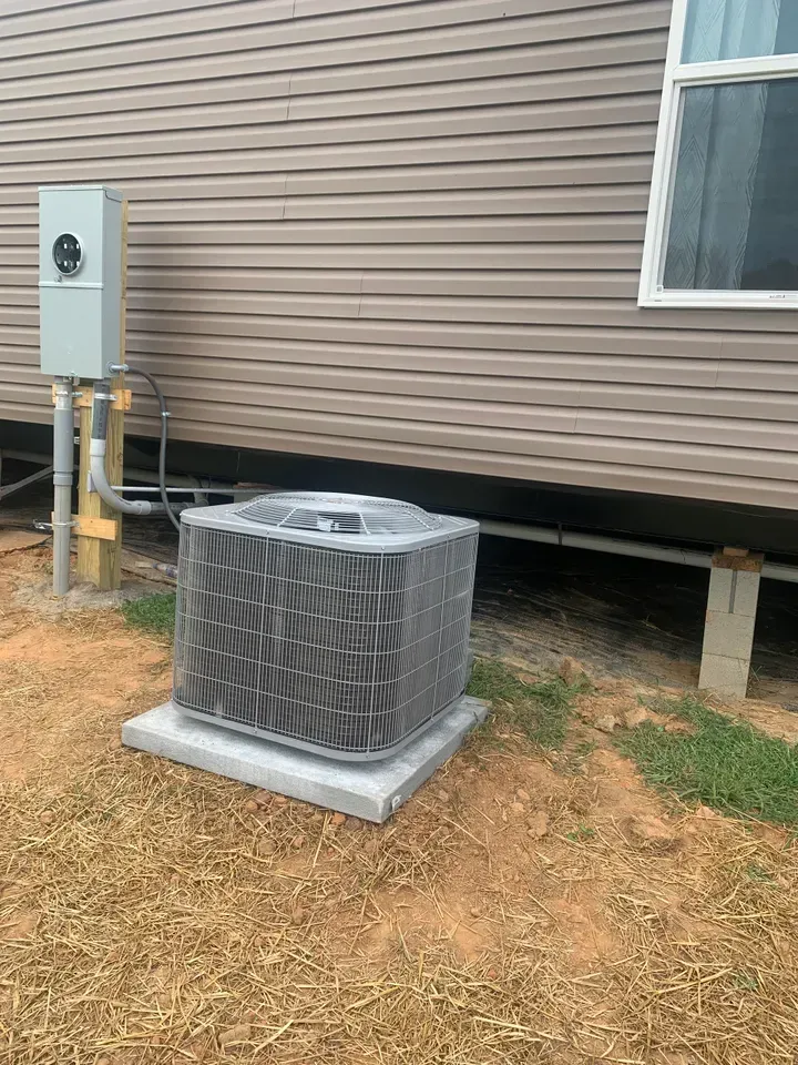 A large air conditioner is sitting in front of a house.