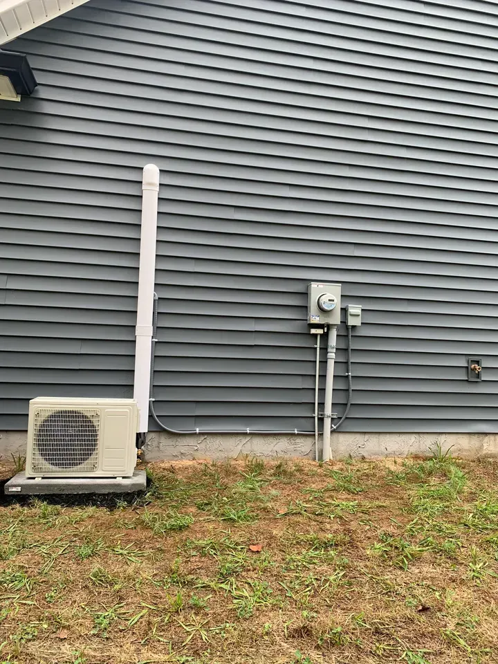 A white air conditioner is sitting on the side of a house.