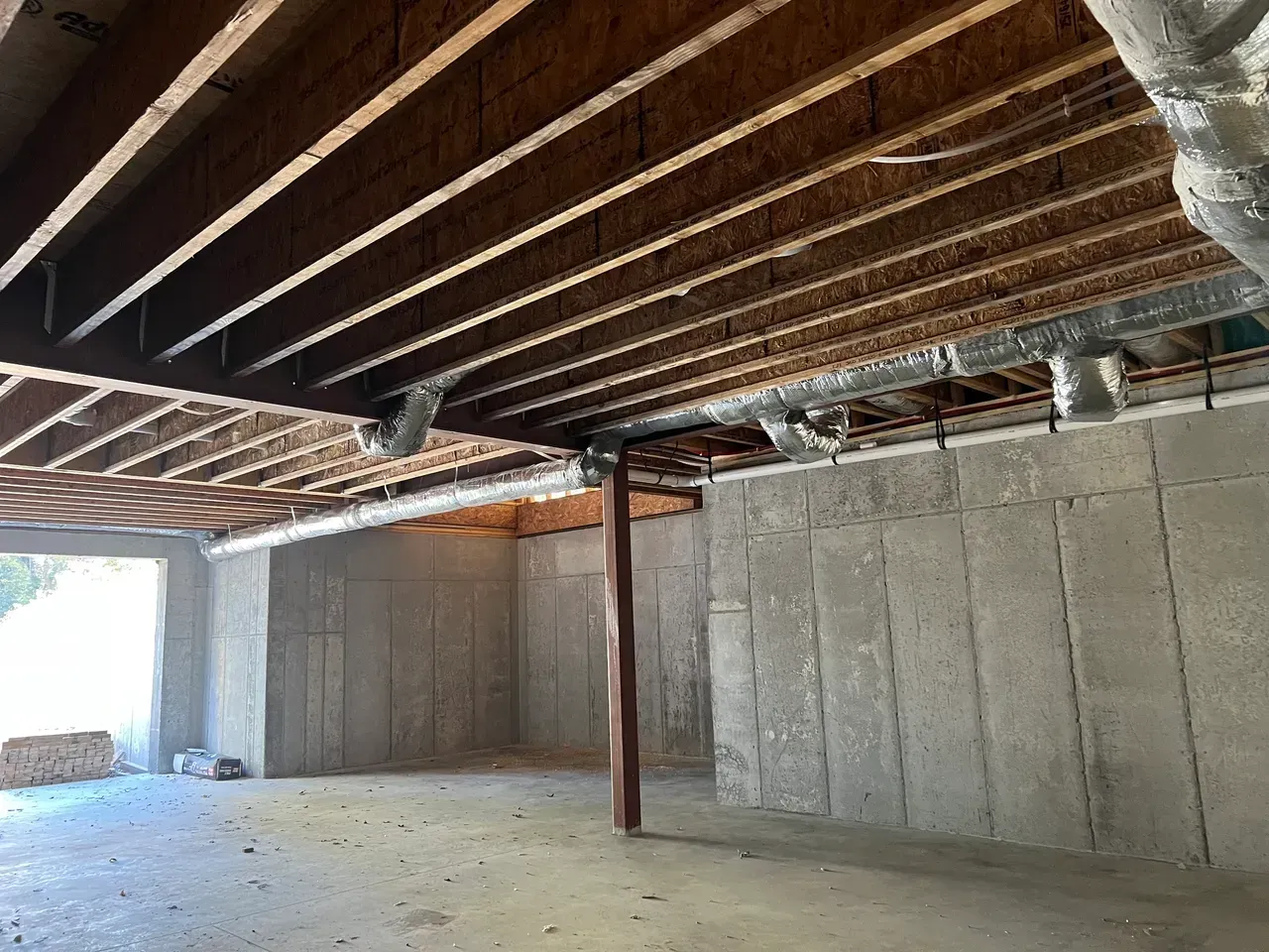 An empty basement with a wooden ceiling and concrete walls.