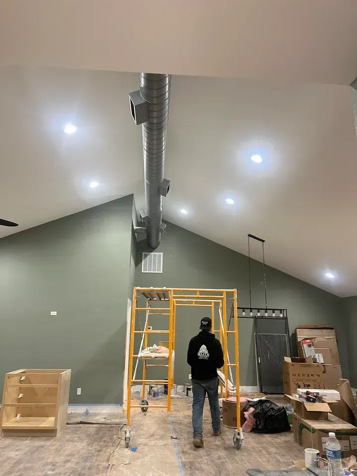 A man is standing on a scaffolding in a room.