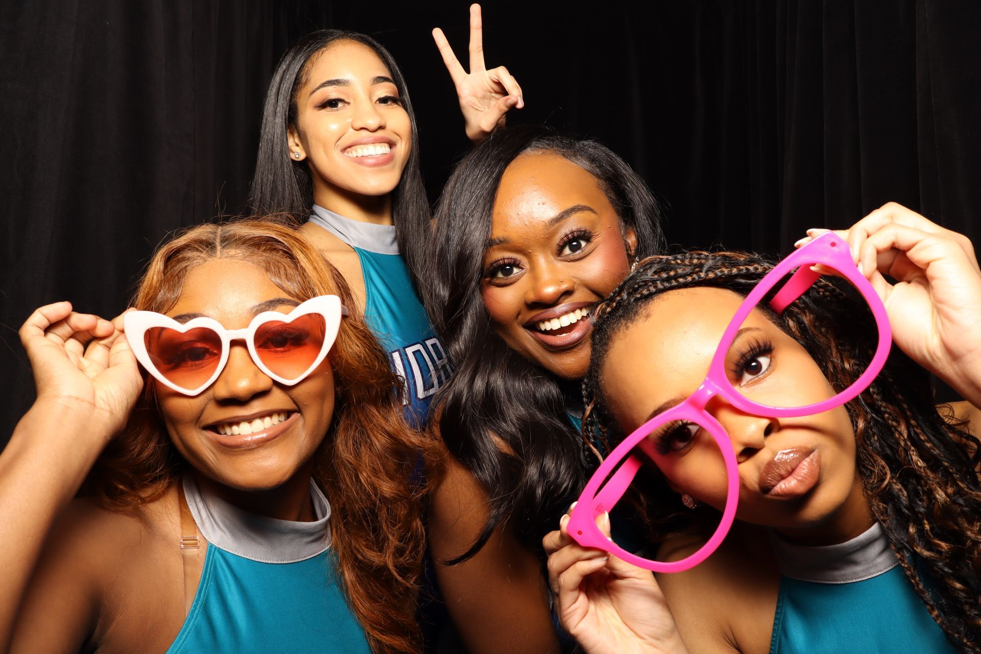 A group of women wearing heart shaped sunglasses are posing for a picture