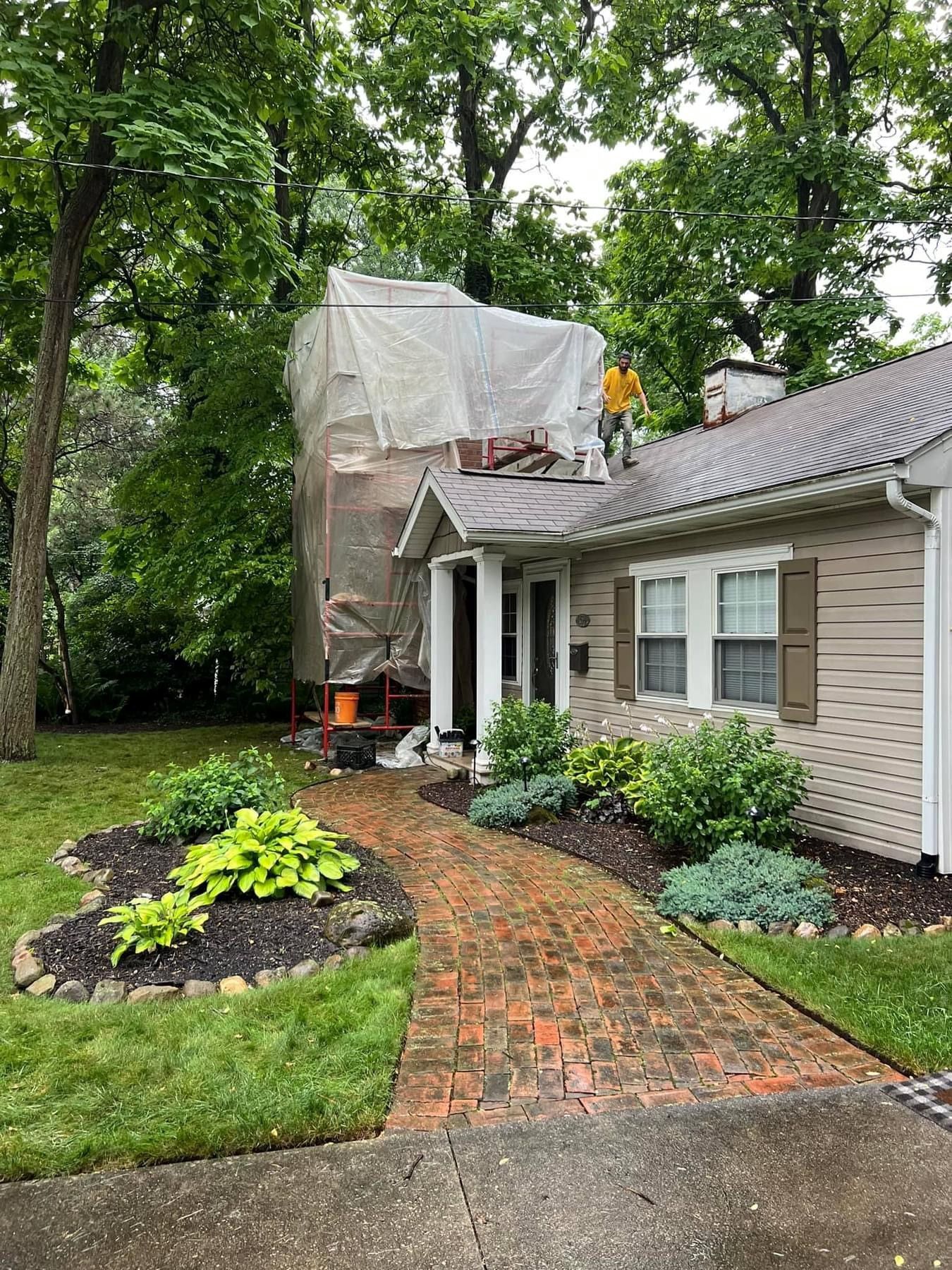 A house with a scaffolding on the roof is being painted