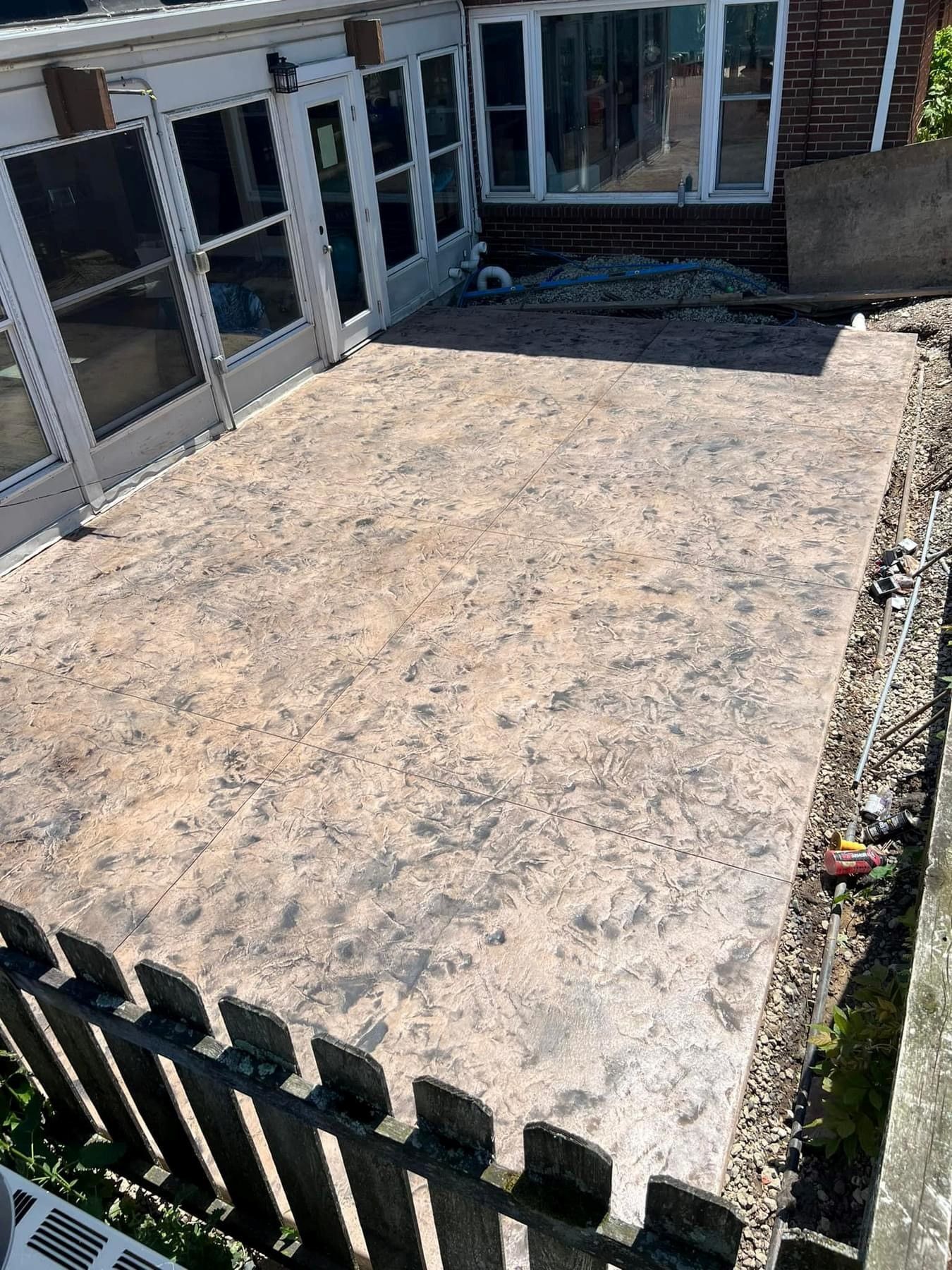 A concrete patio with a wooden fence in front of a house