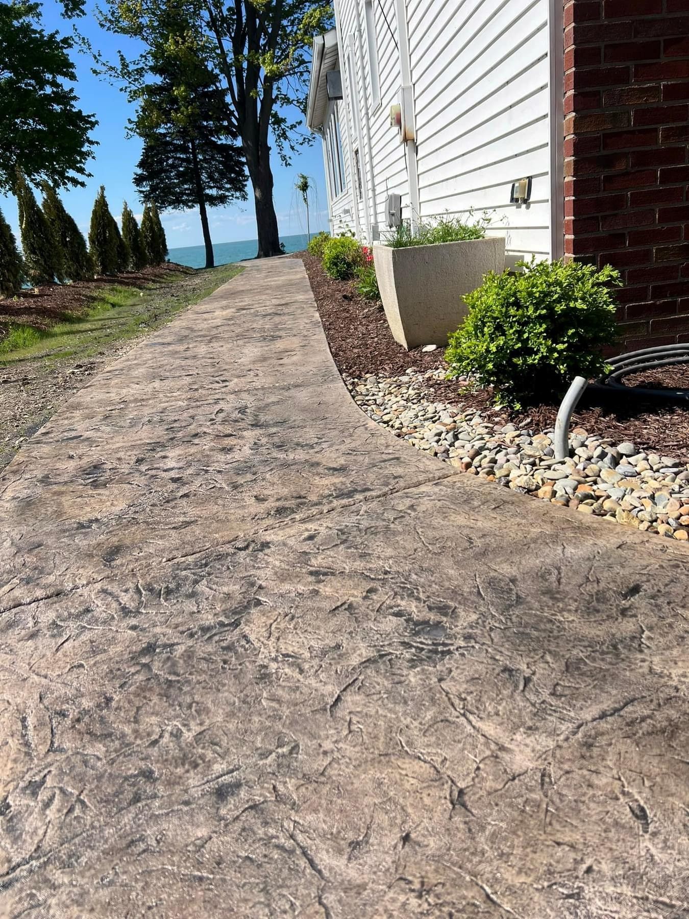 A concrete walkway leading to a house with a view of the ocean