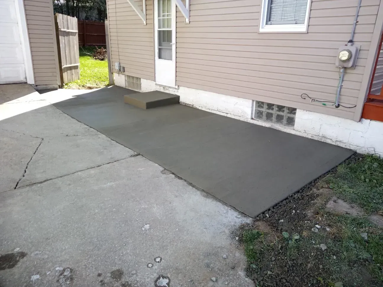 A concrete walkway is being built in front of a house