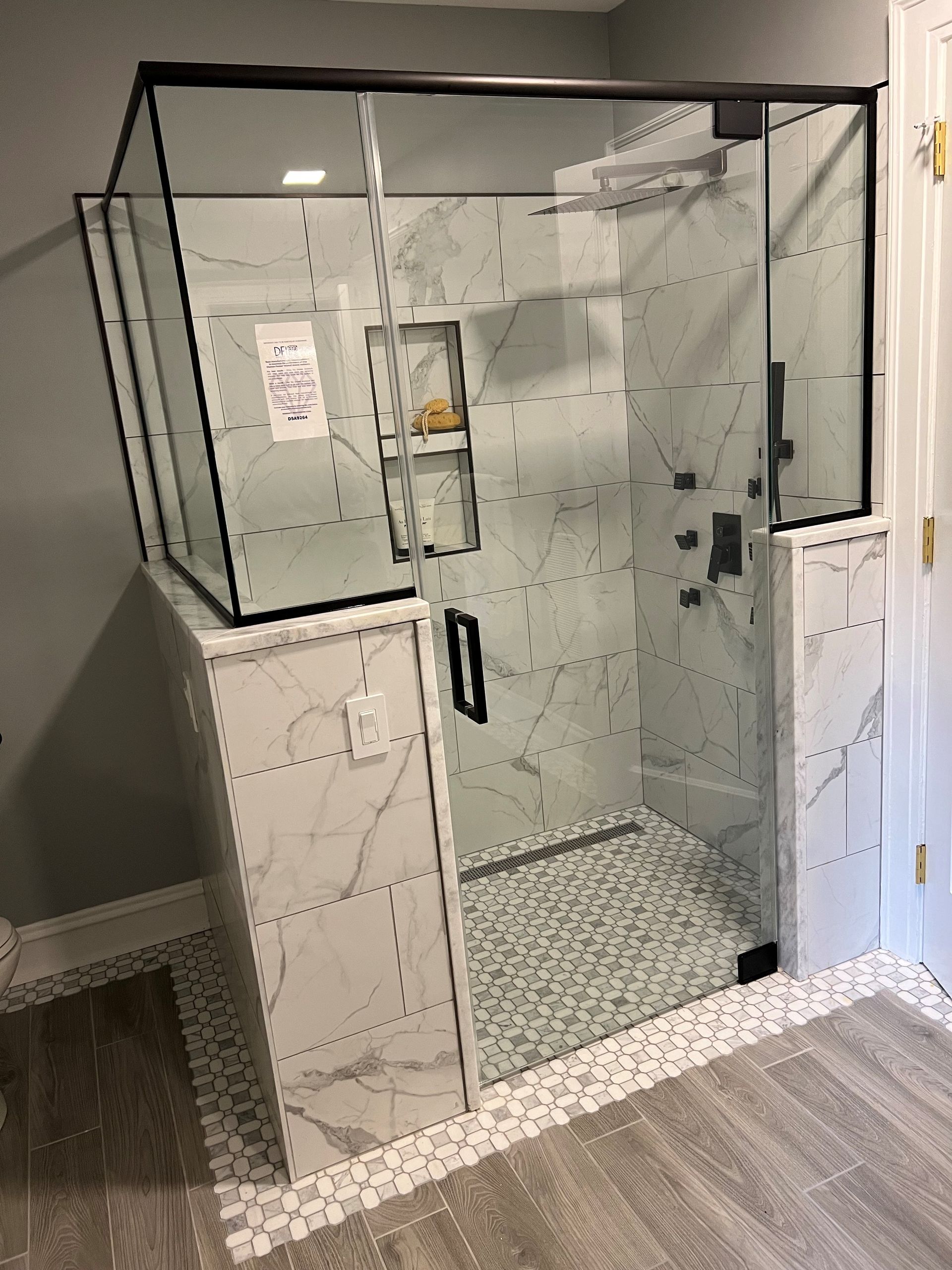 A bathroom with a walk in shower with a glass door.