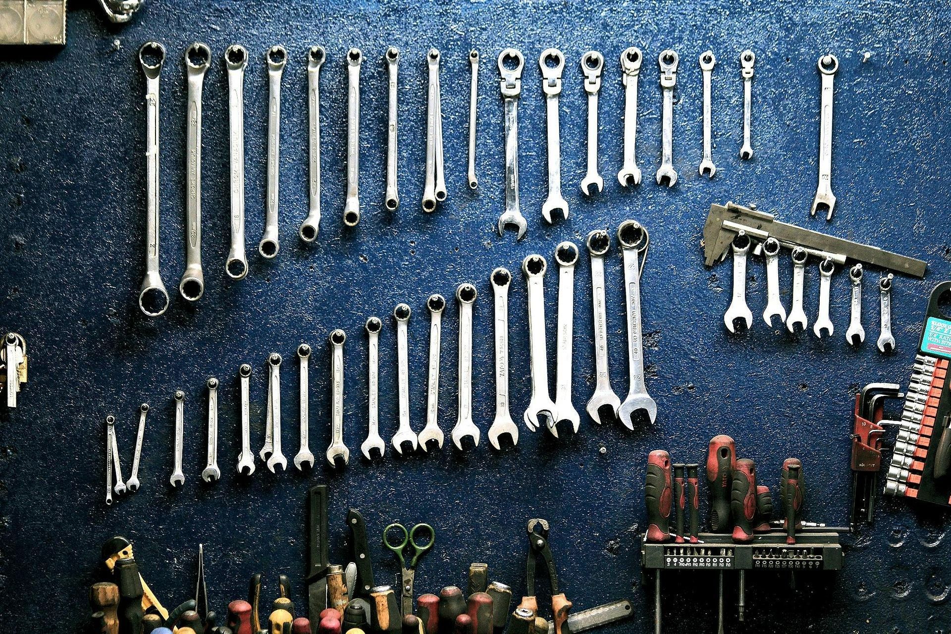 A bunch of tools are hanging on a blue wall