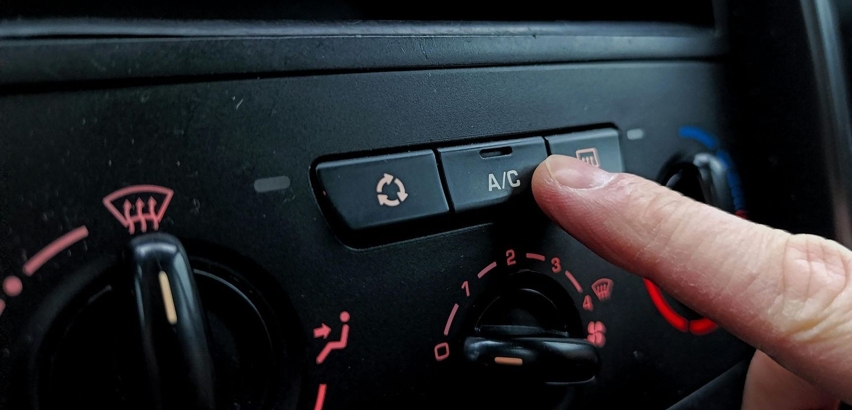A person is adjusting the air conditioning in a car.