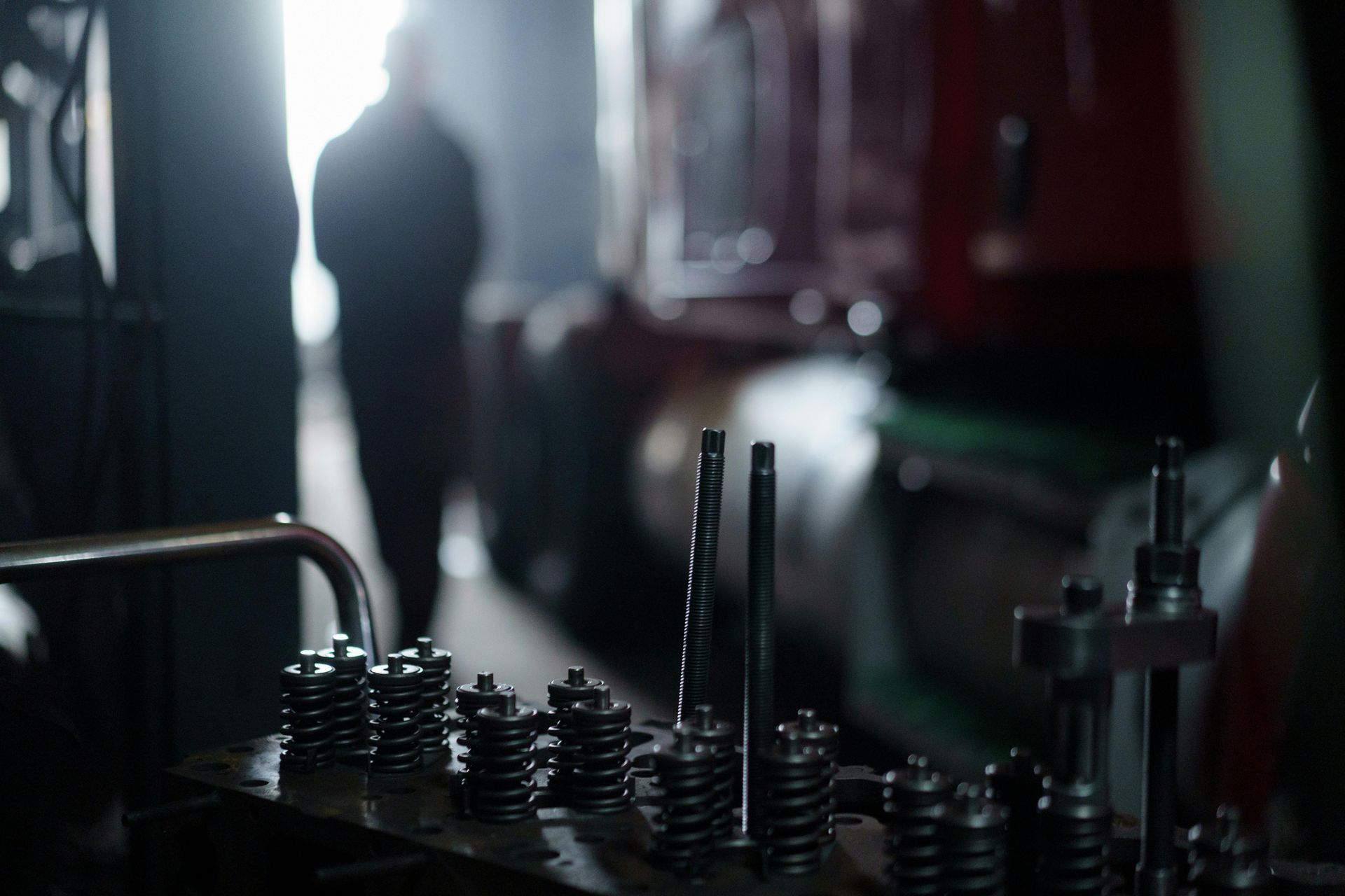 A close up of a machine in a factory with a man in the background.