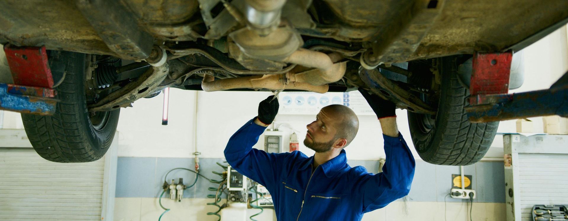 A man is working under a car in a garage.