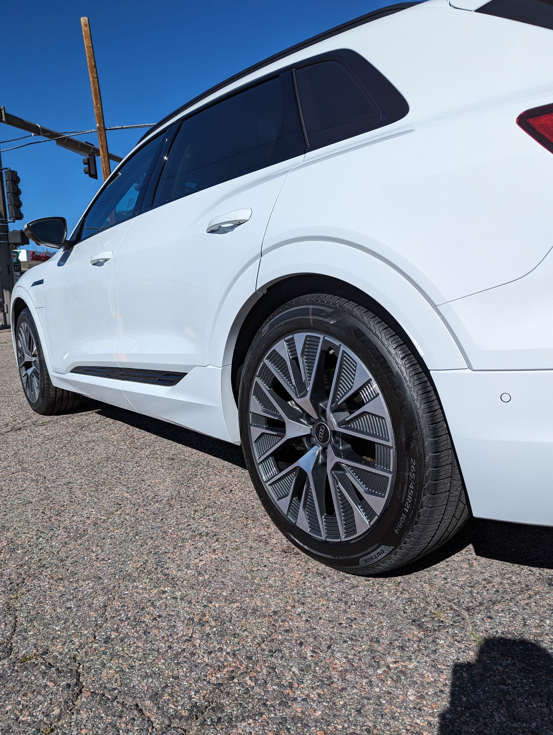 A white car is parked on a gravel road.