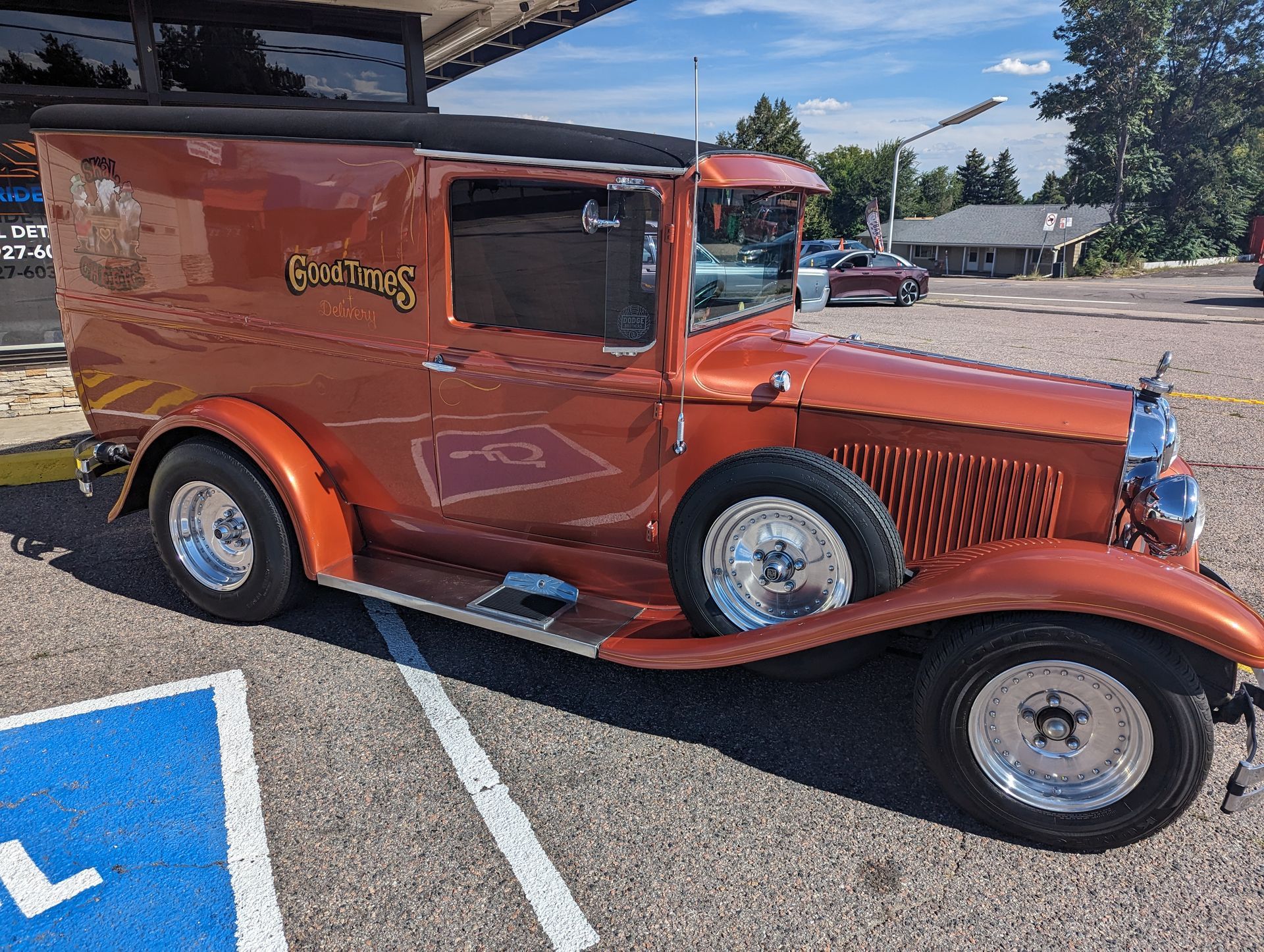 An old orange car is parked in a handicapped parking spot.