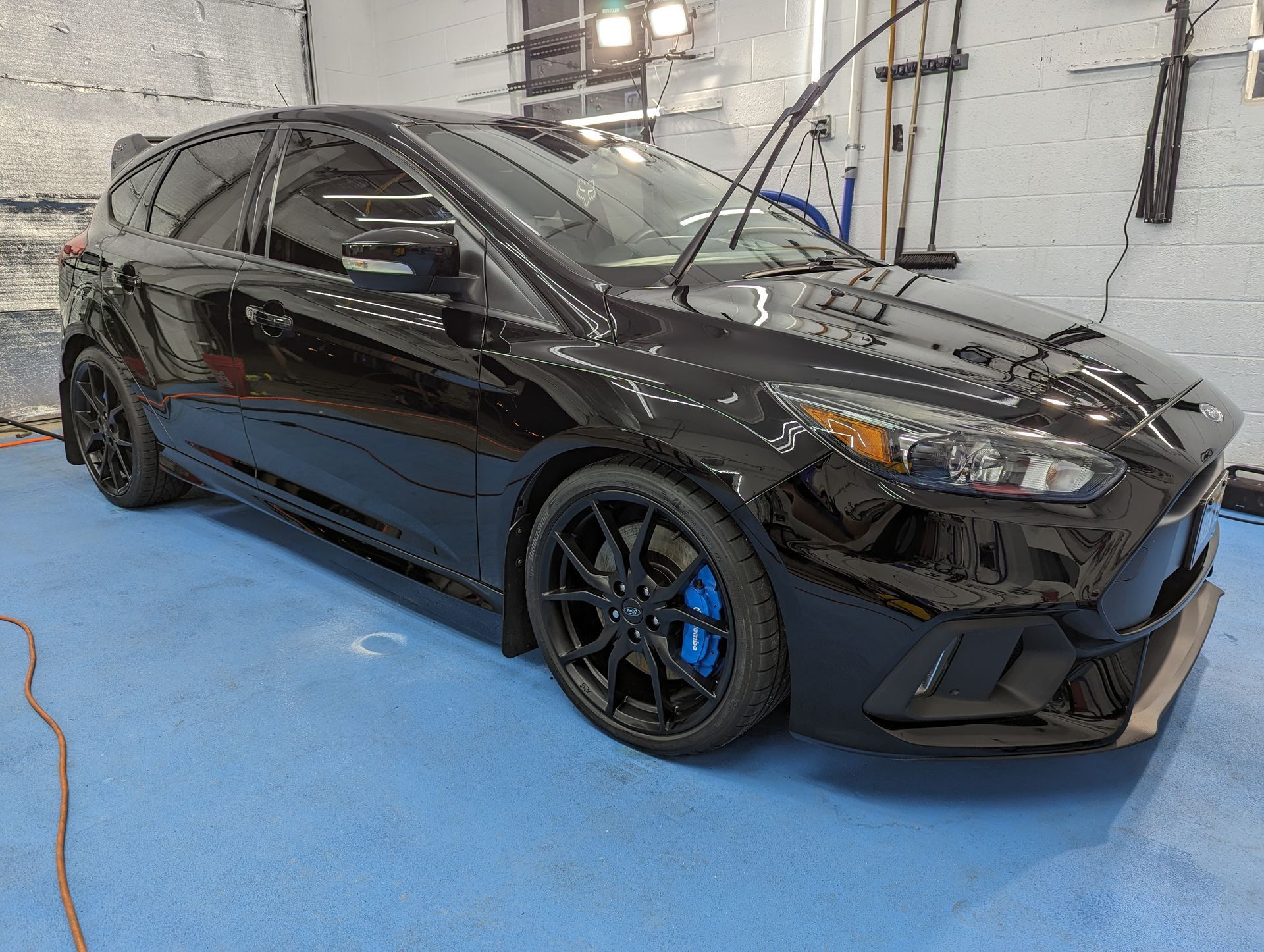 A black ford focus rs is parked in a garage.