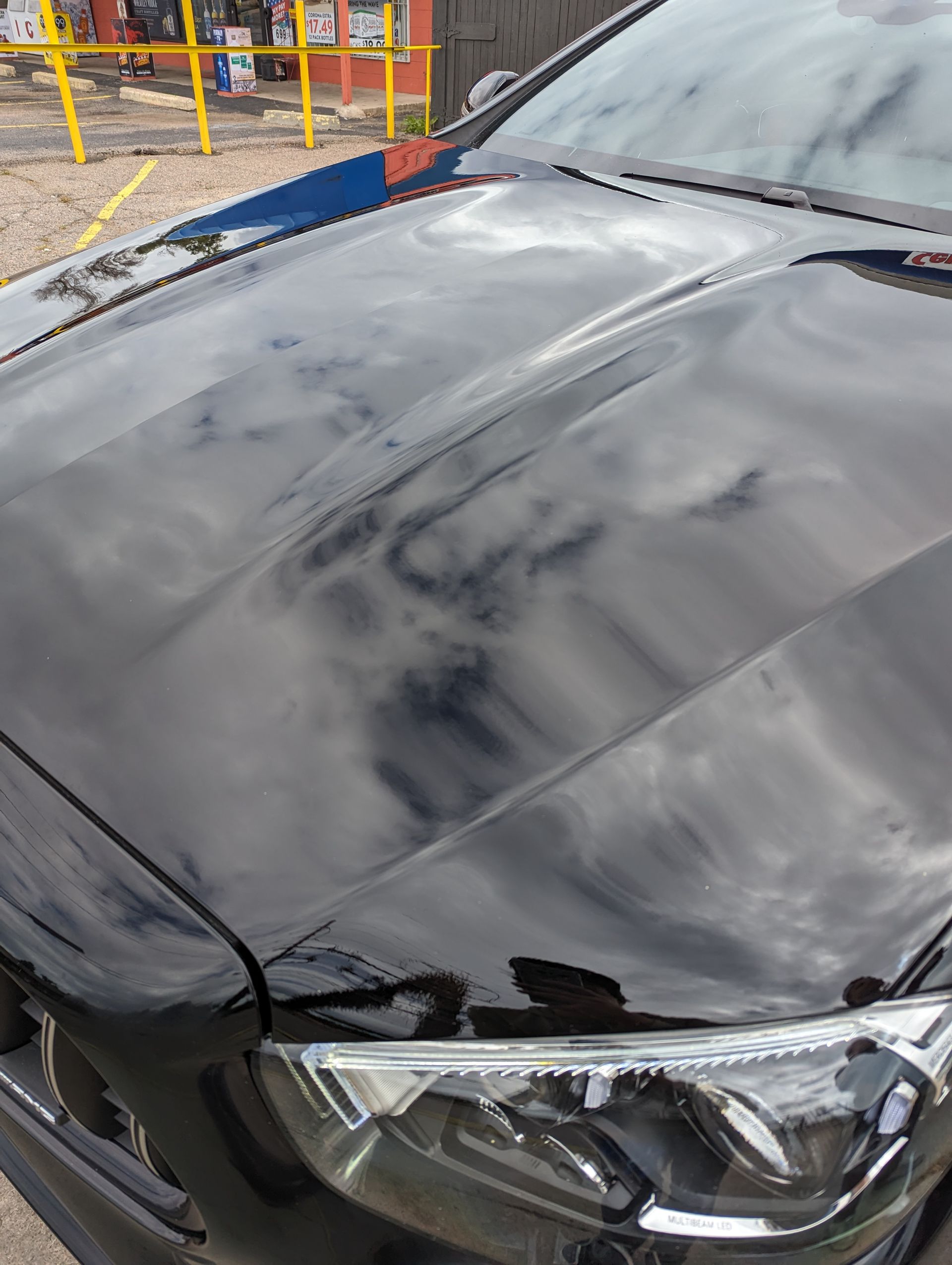 A close up of a black car 's hood and headlights.
