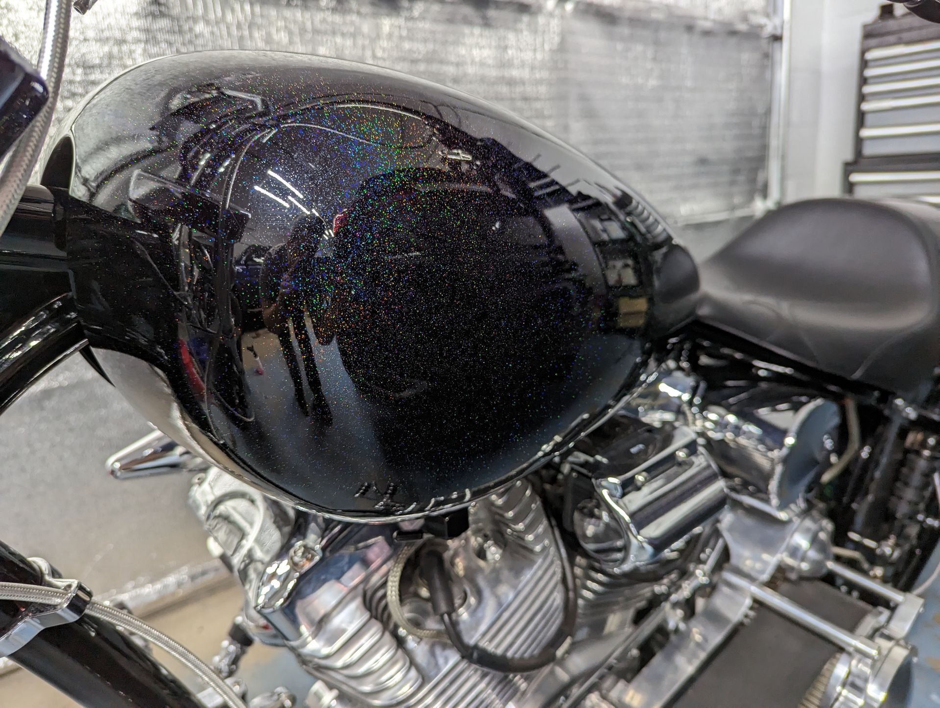 A motorcycle with a black tank and a black seat is parked in a garage.
