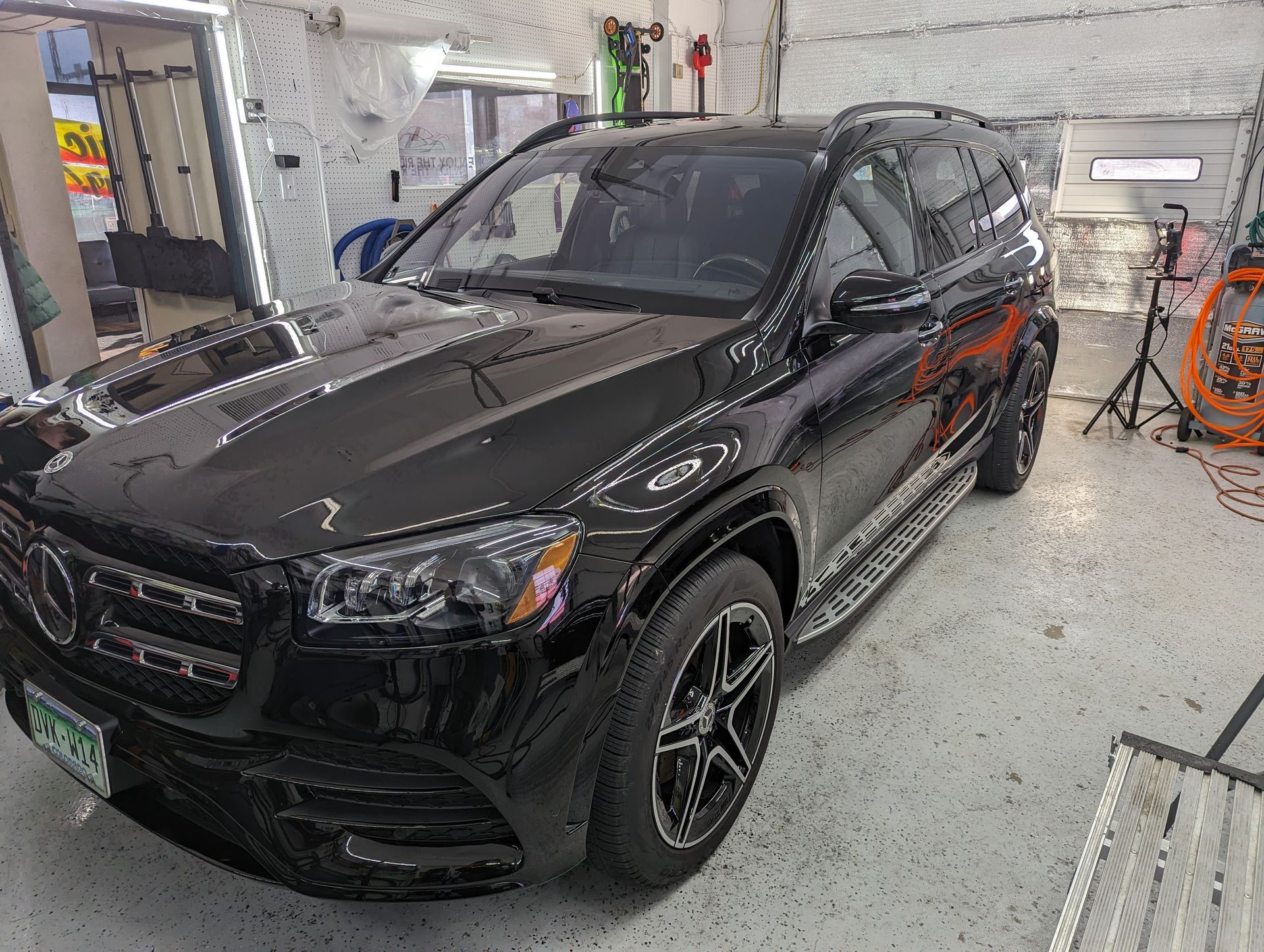 A black mercedes benz gls 550 is parked in a garage.