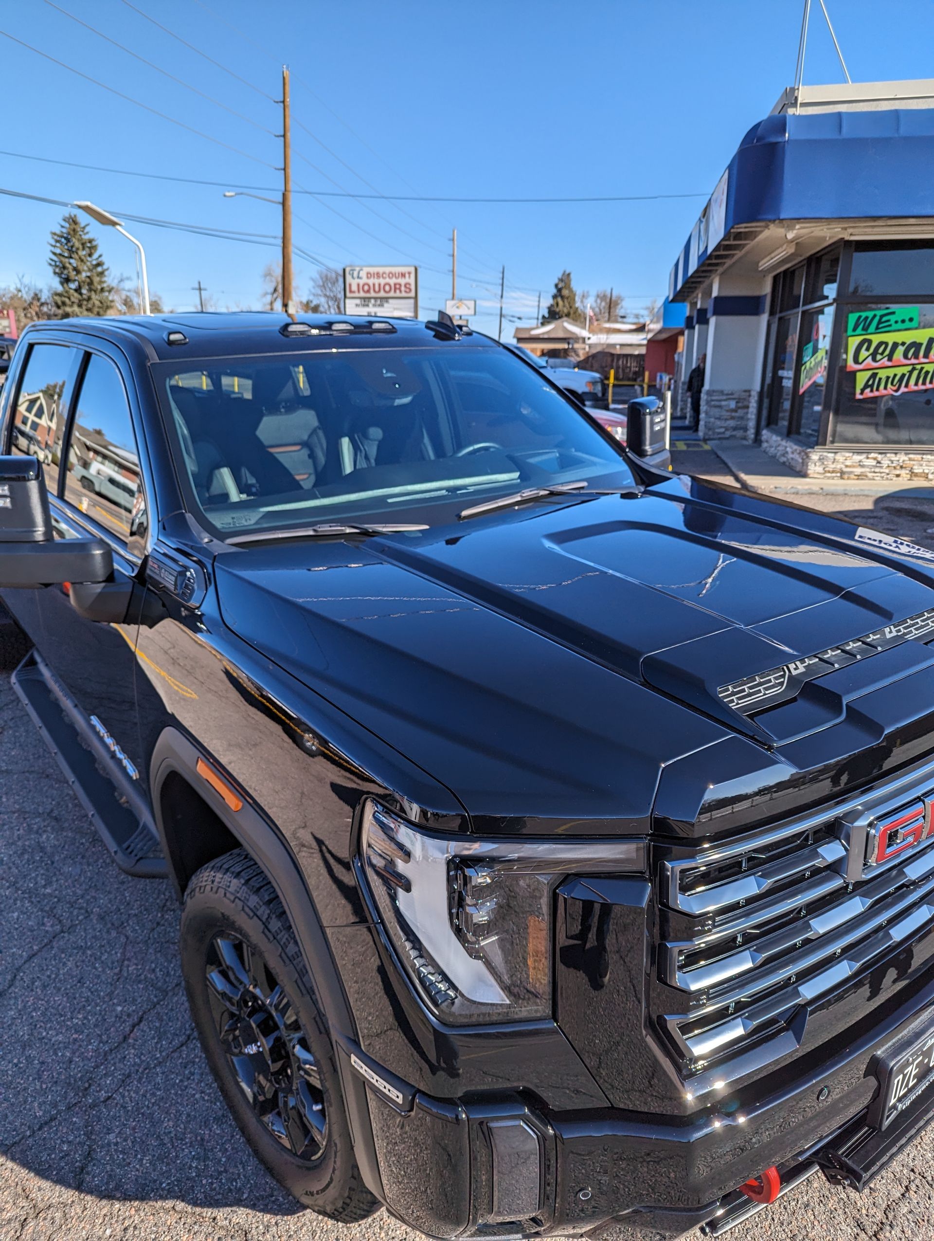 A black gmc truck is parked in front of a store.