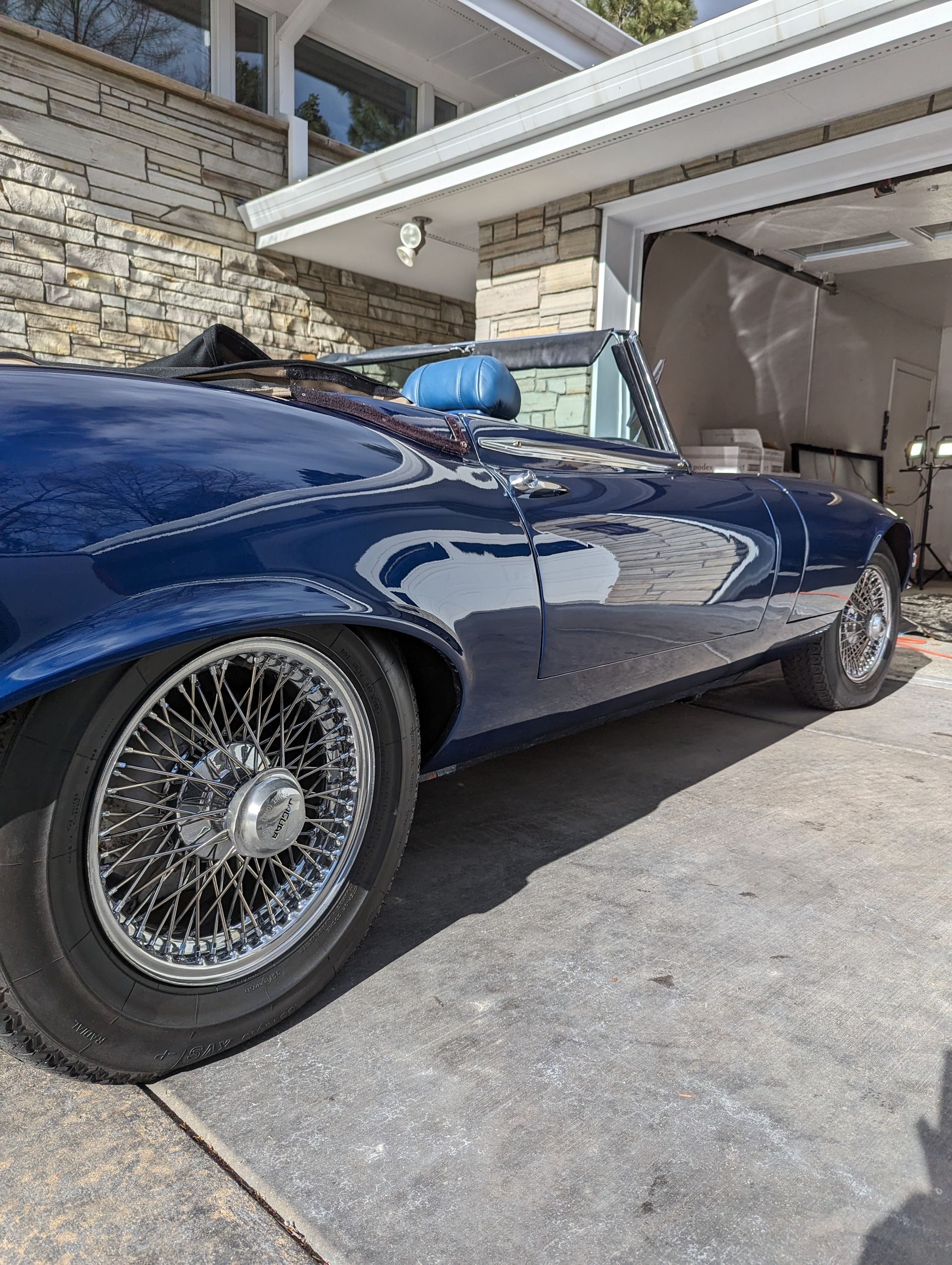 A blue car is parked in front of a garage.