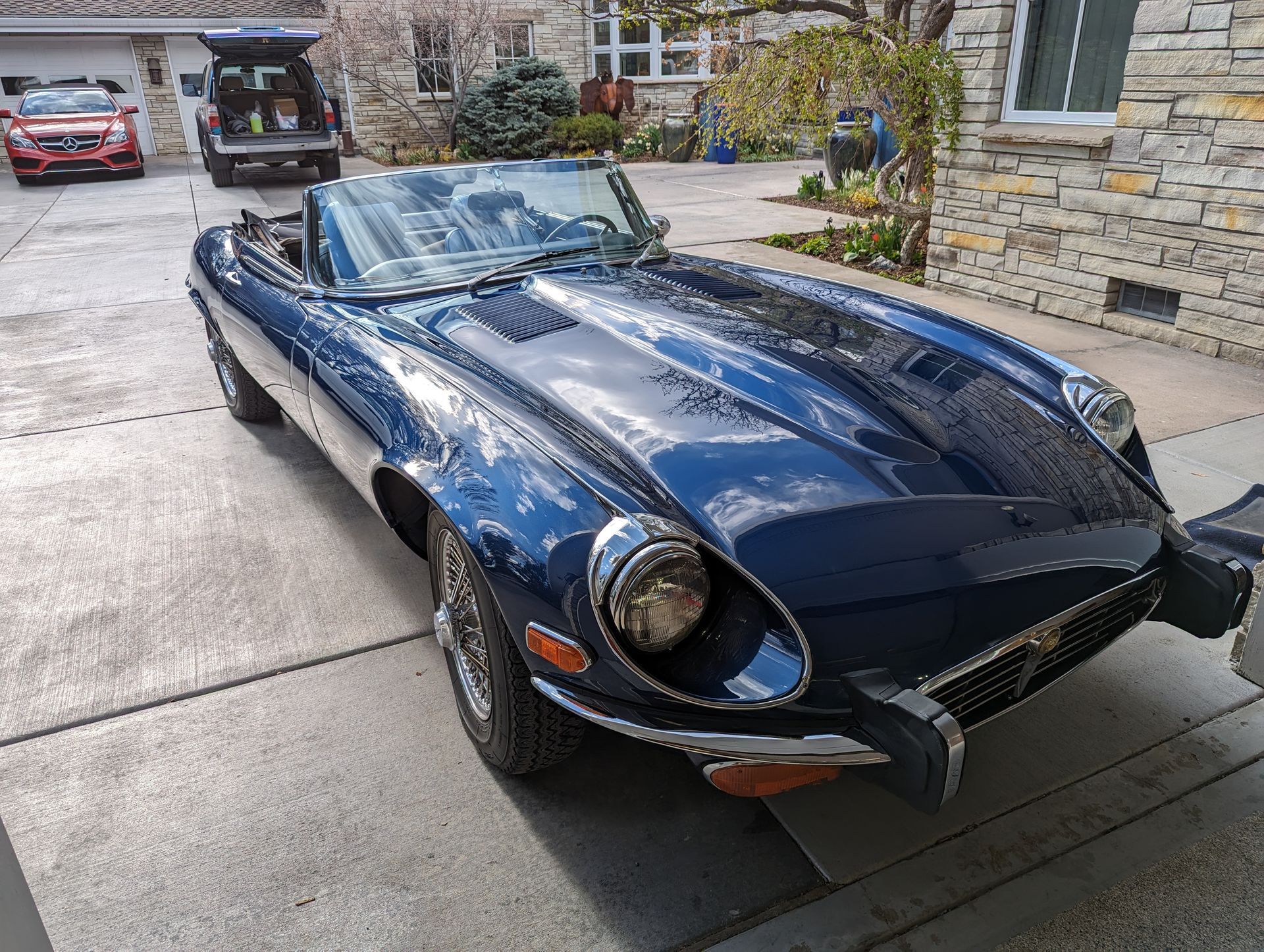 A blue sports car is parked in a driveway in front of a house.