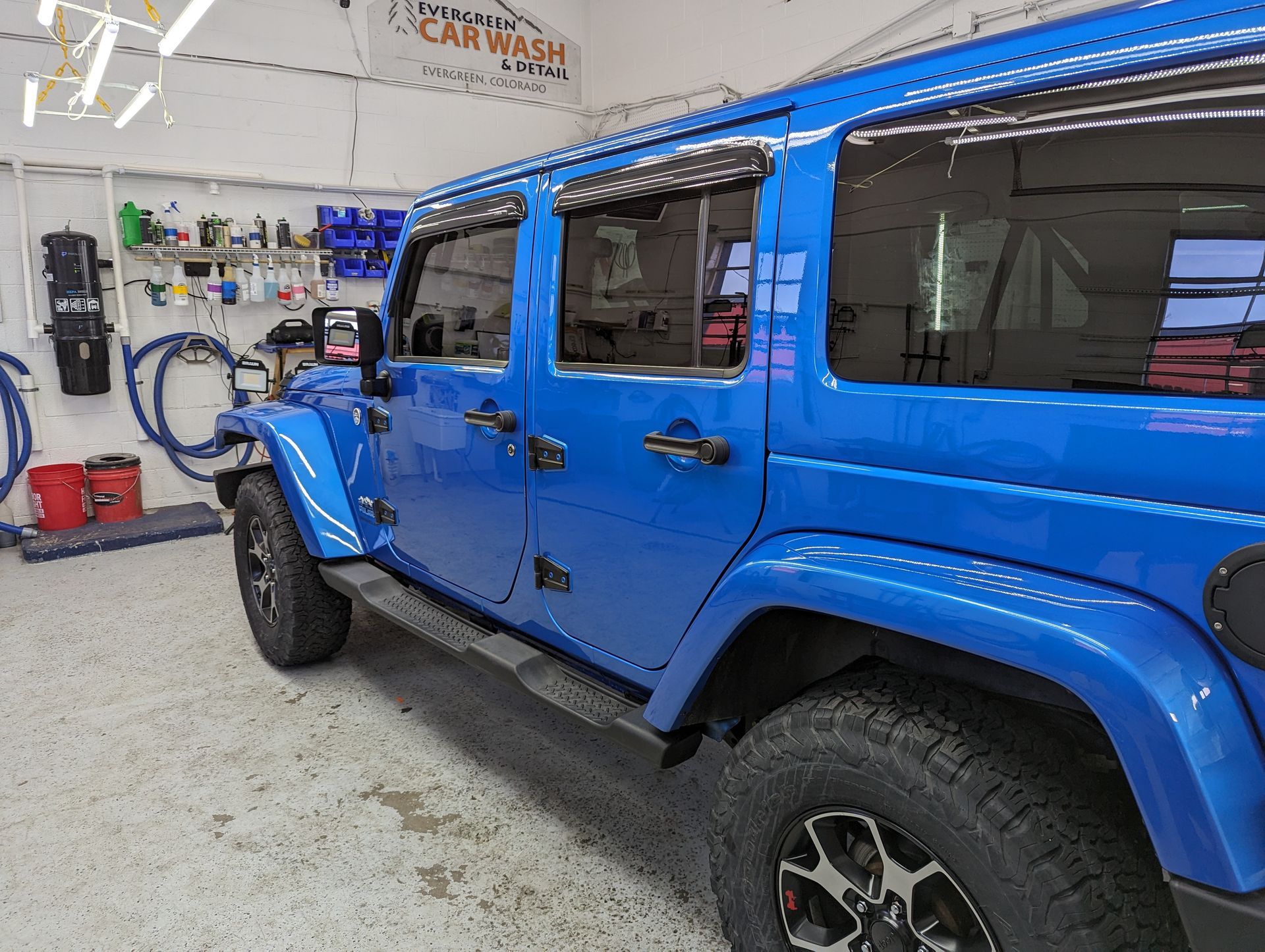 A blue jeep is parked in a car wash.
