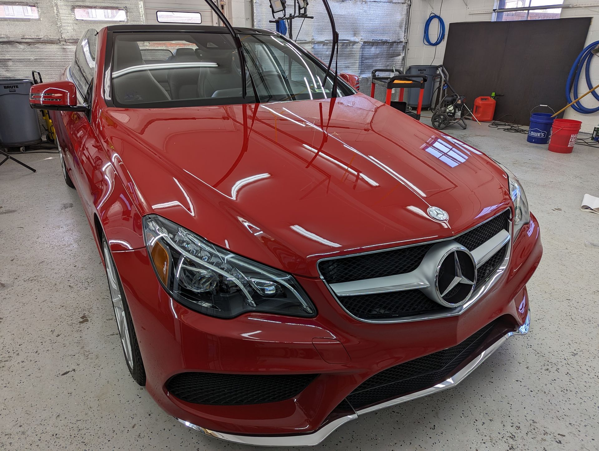 A red mercedes is parked in a garage.