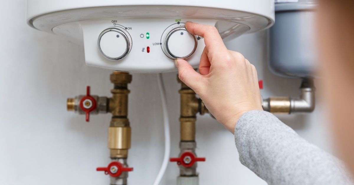 A person adjusting a dial to change the settings on a water heater.