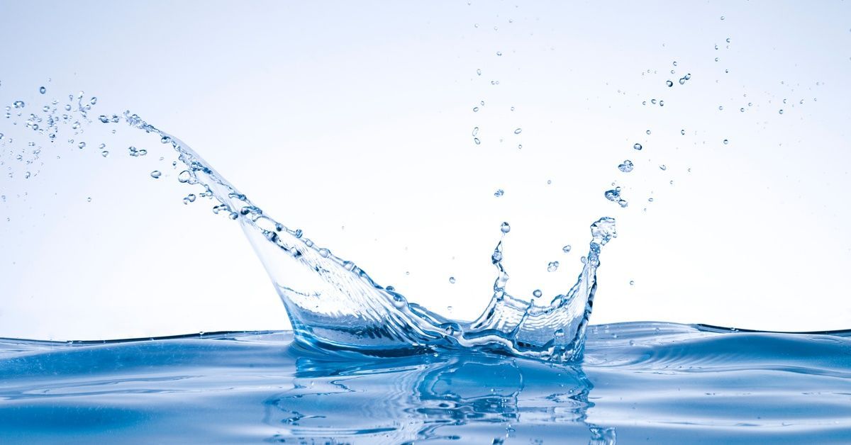 A pool of clear water with a splash erupting from the center.