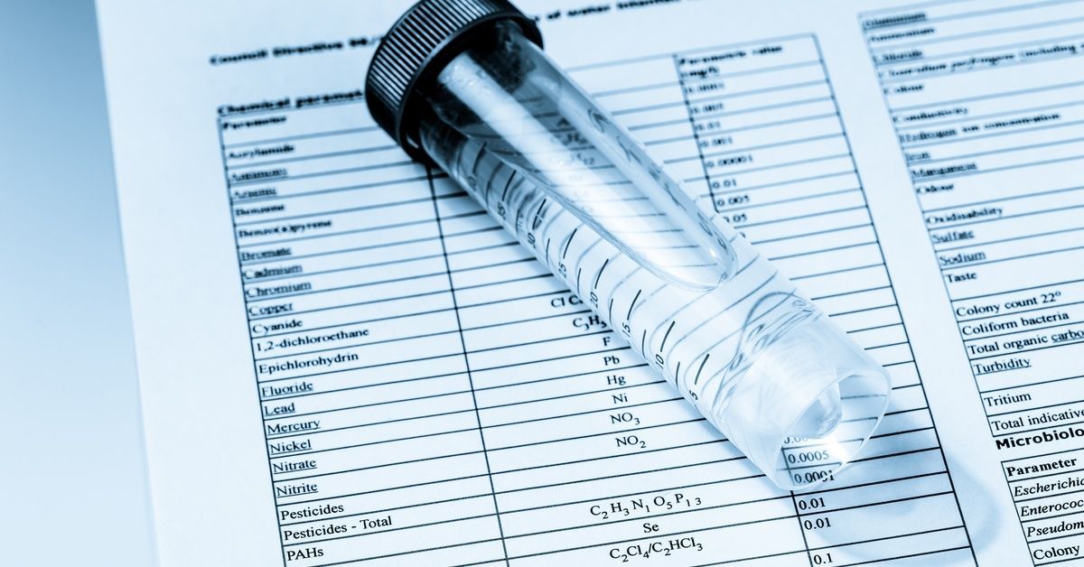 A water quality test sheet with a test tube laid on top, on a table.