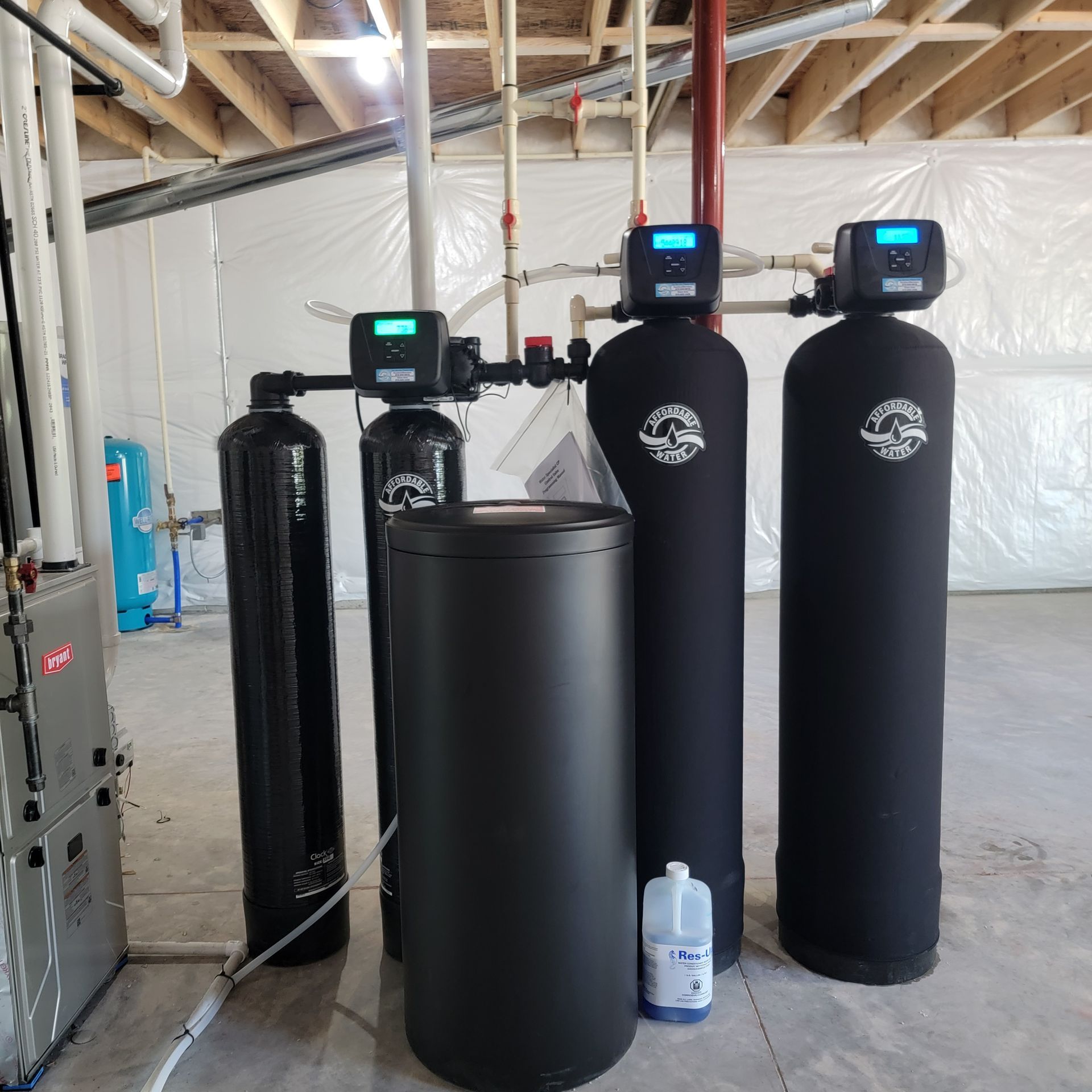 Black water filtration tanks and a black barrel in a basement utility area