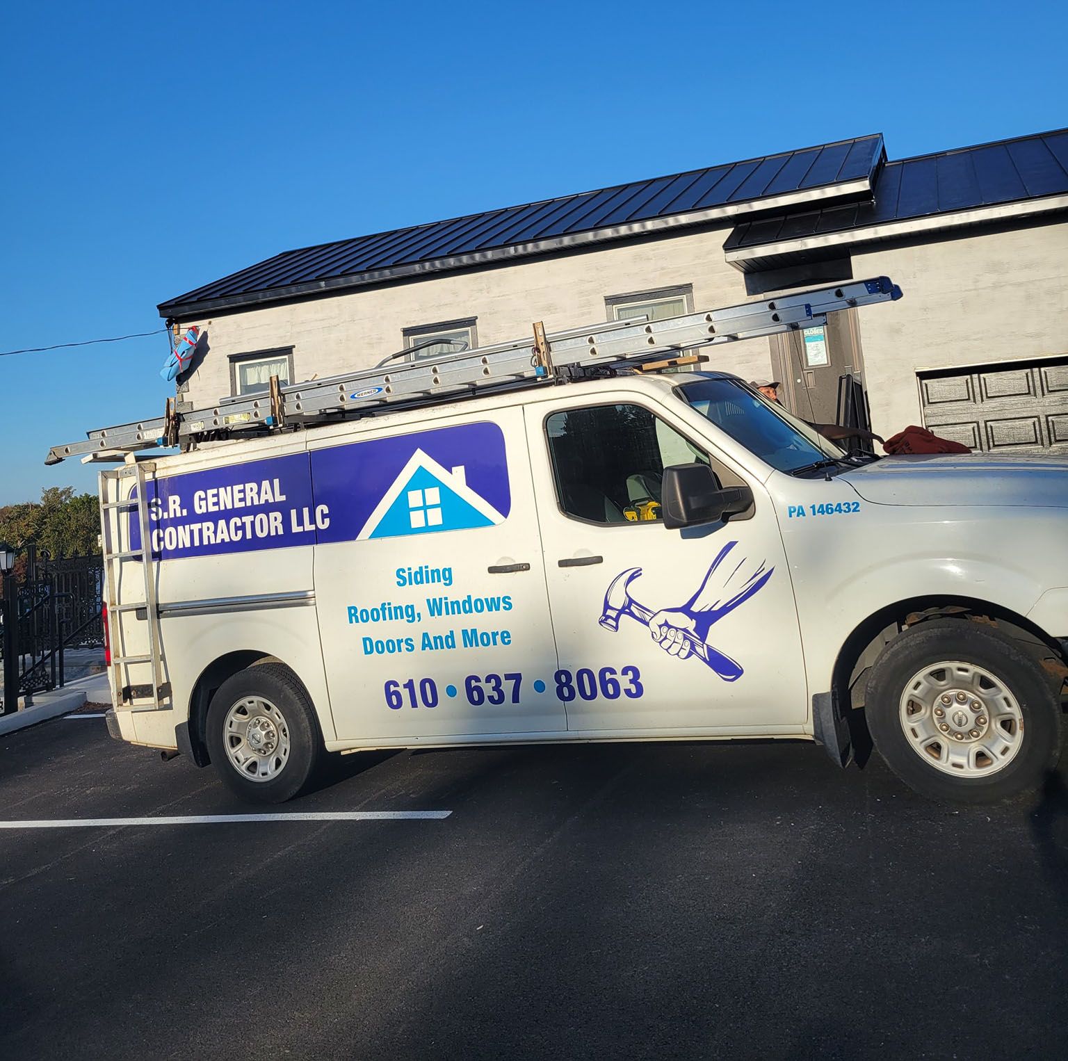White work van with logo for J.R. General Contractor, parked in front of a building. Ladder on top.