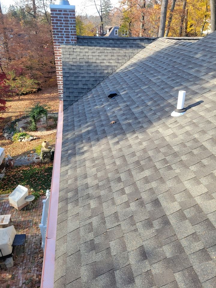 Roof with asphalt shingles and a brick chimney, seen from above.