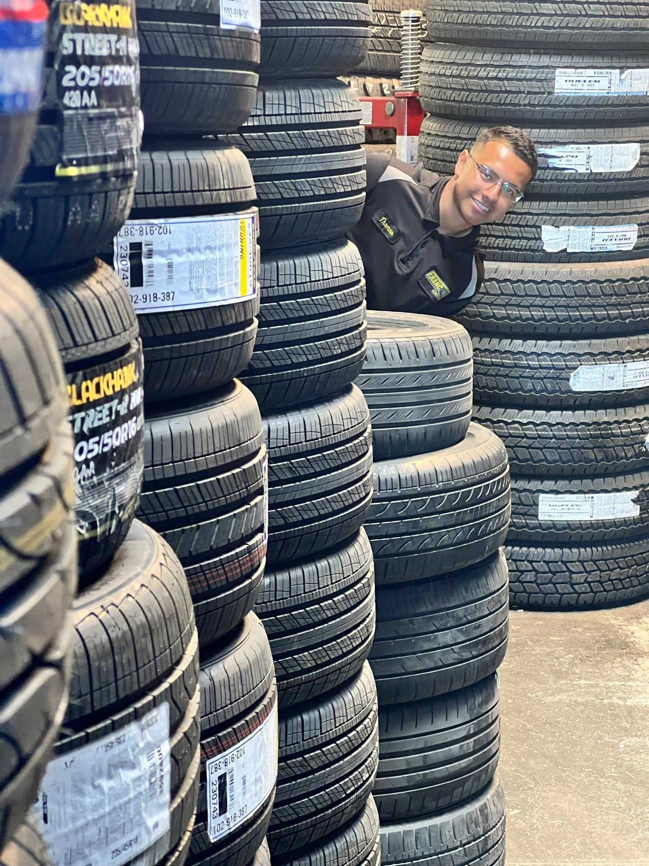 Man peeks from between stacks of tires.