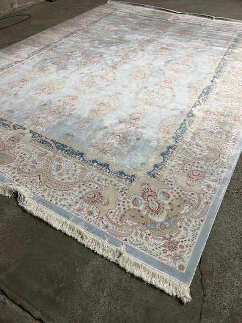A large rug is sitting on top of a concrete floor.