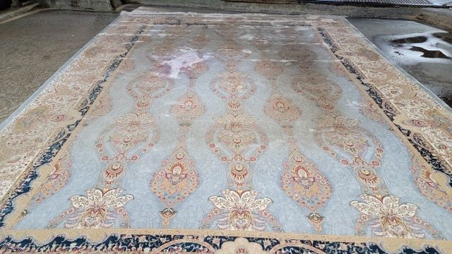 A large rug is sitting on top of a cement floor.