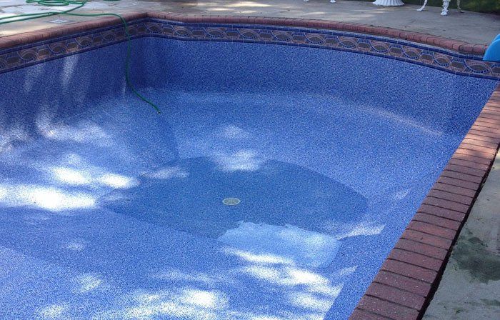 Empty blue-tiled swimming pool with brick border, awaiting water