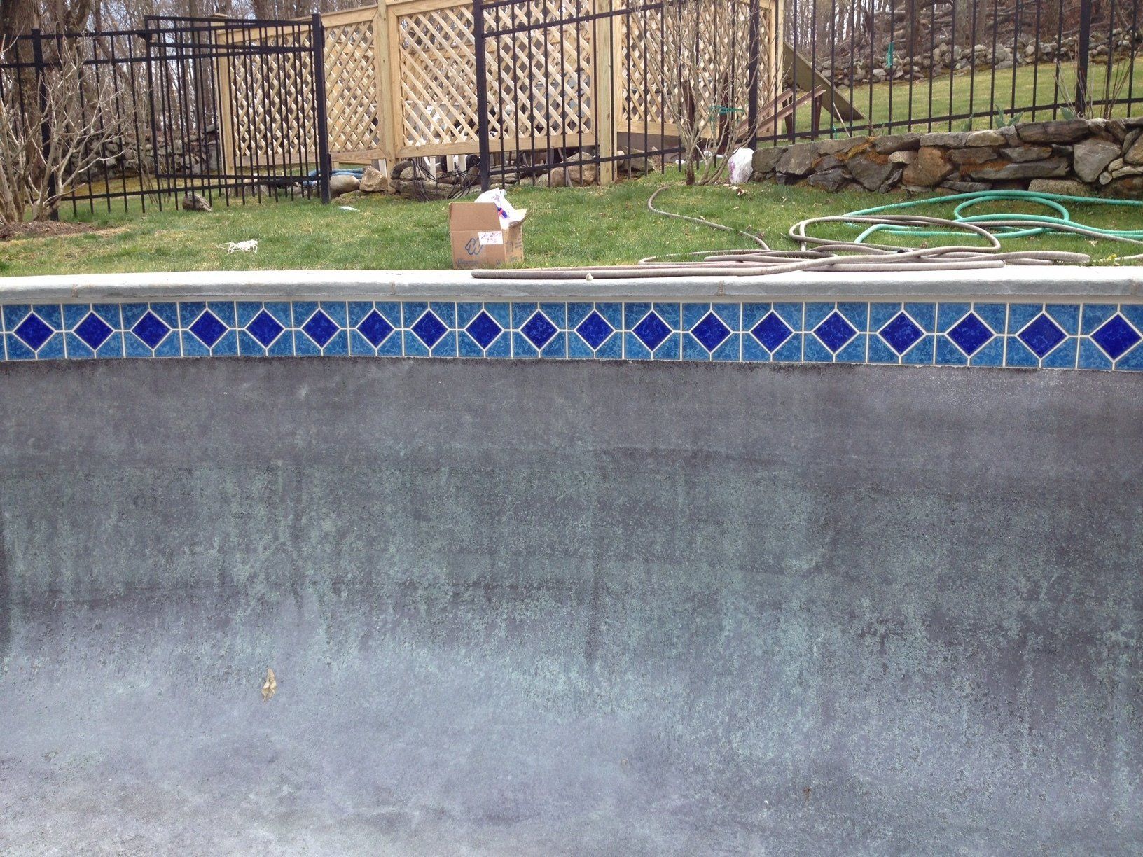 Close-up of pool with blue tiled border and a weathered gray interior, set outdoors