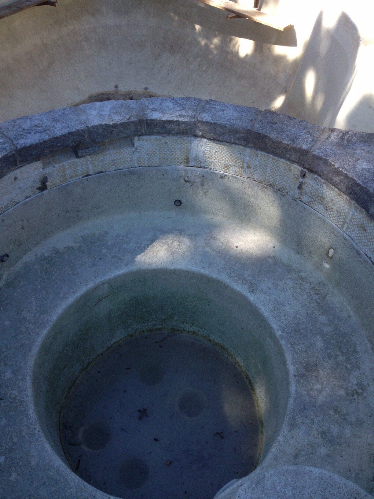 Overhead view of a weathered, tiered stone structure with a central circular opening
