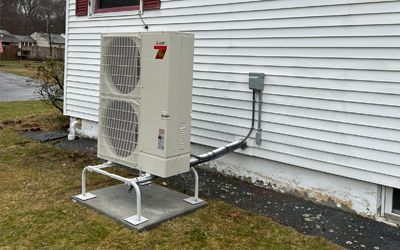 A large air conditioner is sitting on the side of a house.